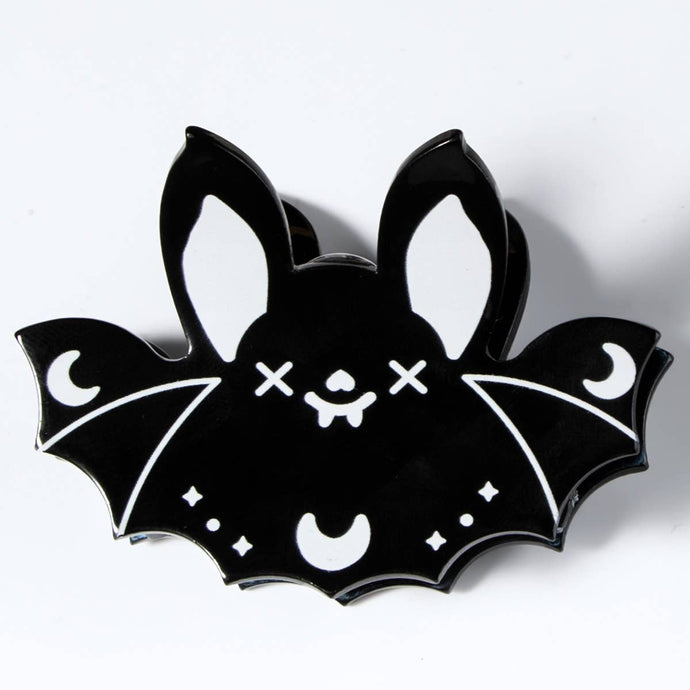 Black bat-shaped hair clip with white accents on a white background