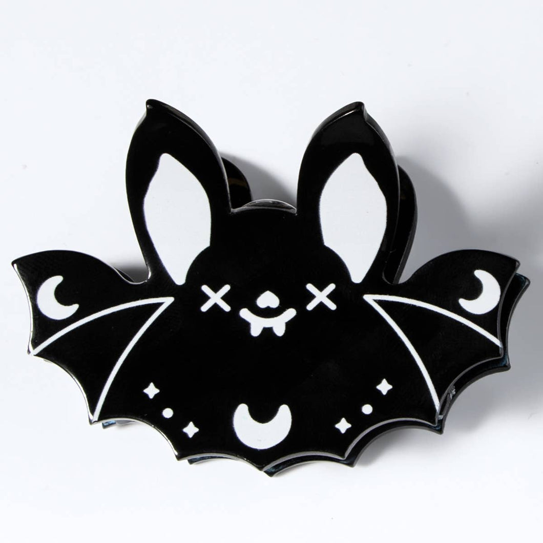 Black bat-shaped hair clip with white accents on a white background