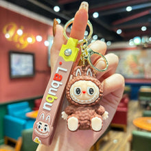 Load image into Gallery viewer, Brown Labubu Keychain with cartoon character held in a hand against a blurred indoor background
