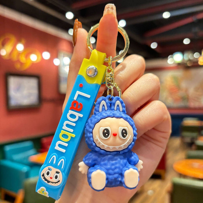 Blue Labubu Keychain with a cartoon character held by a hand in an indoor setting