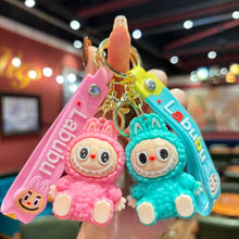 Load image into Gallery viewer, Two colorful Labubu keychains with cartoon characters held in a hand against a blurred indoor background.
