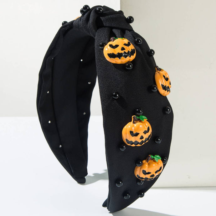 Black headband with orange pumpkin decorations on a white background